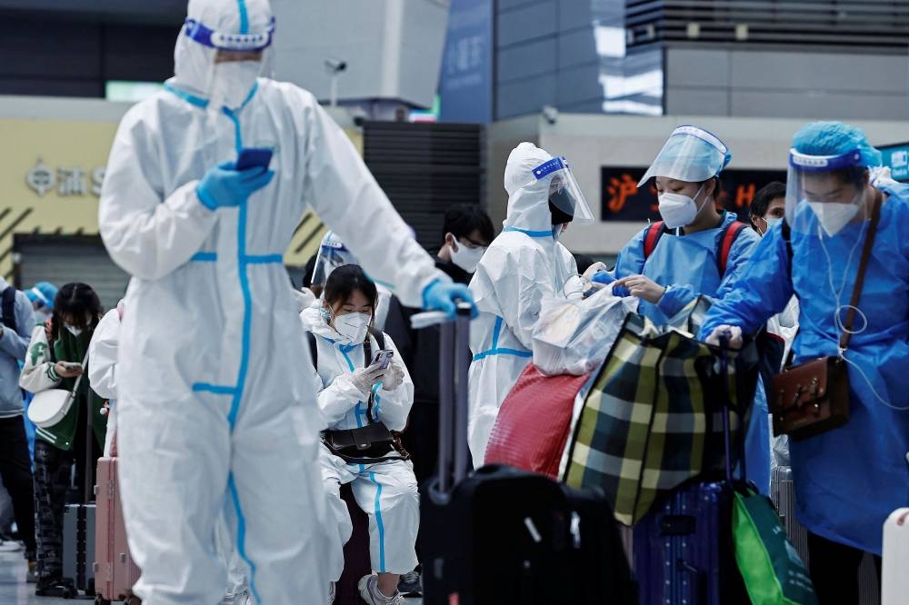 Travellers in protective suits wait at a railway station in Shanghai, China May 17, 2022. ― cnsphoto via Reuters