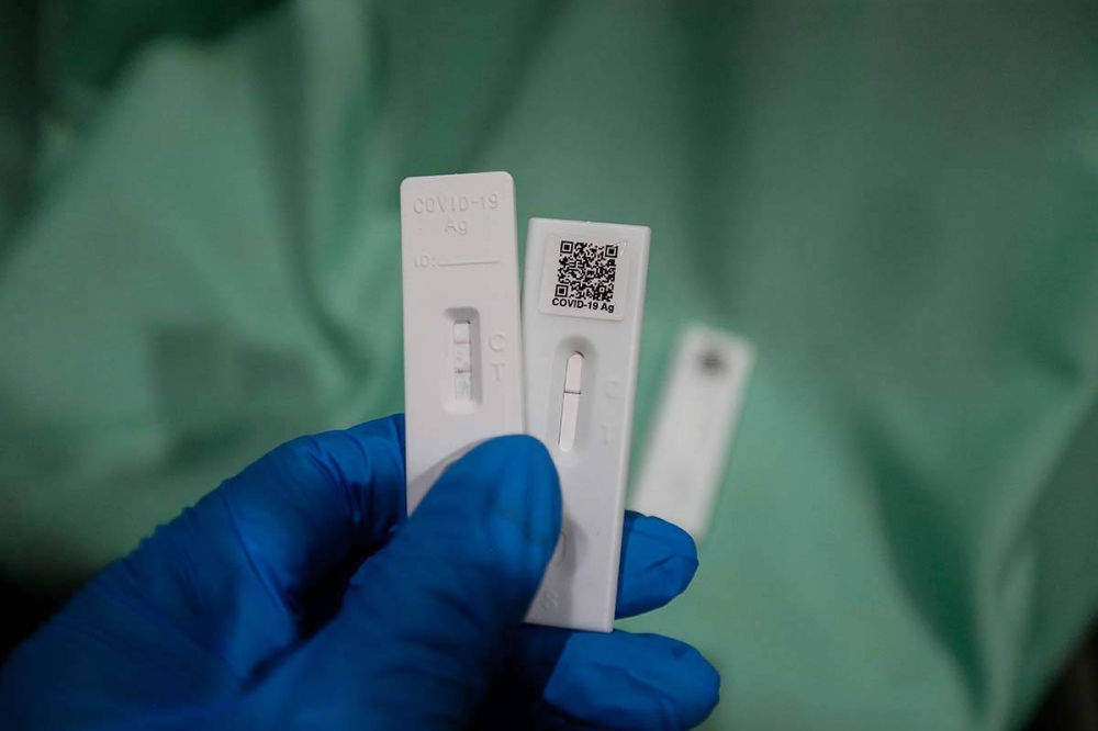 A health personnel holds up Covid-19 test strips indicating a positive and negative result in Seberang Jaya April 7, 2022. — Picture by Sayuti Zainudin