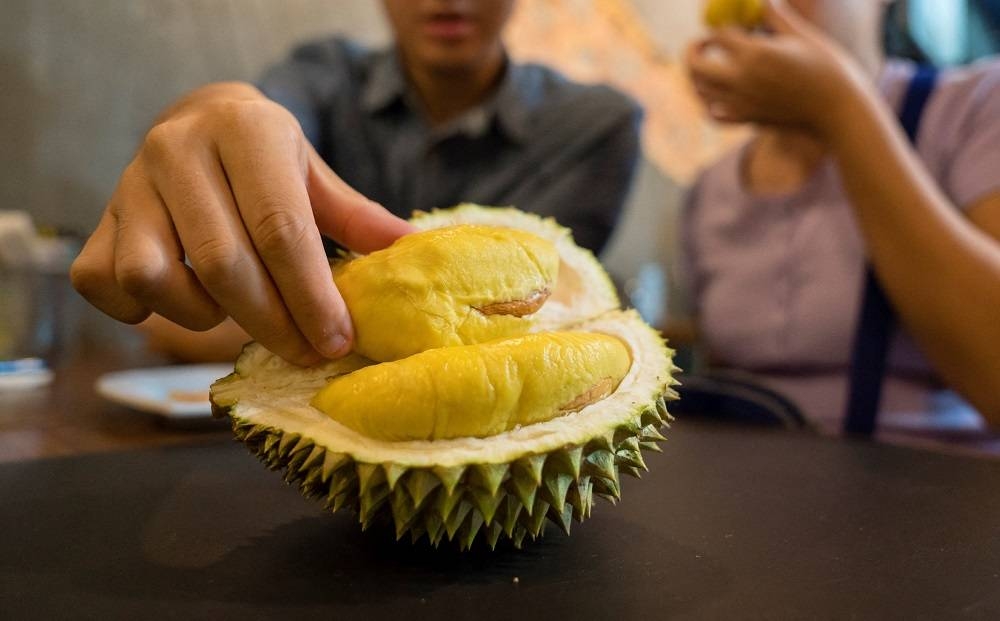 Customers at a shop in Singapore eating durians. — AFP pic 
