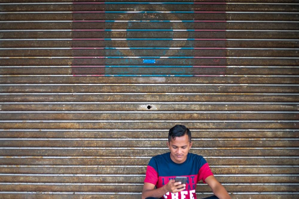 A man sits in front of a PKR flag painted on a roller shutter in Petaling Jaya June 12, 2019. PKR’s Election Committee (JPP) has revealed that eight divisions in four states will have to redo their elections. - Picture by Ahmad Zamzahuri