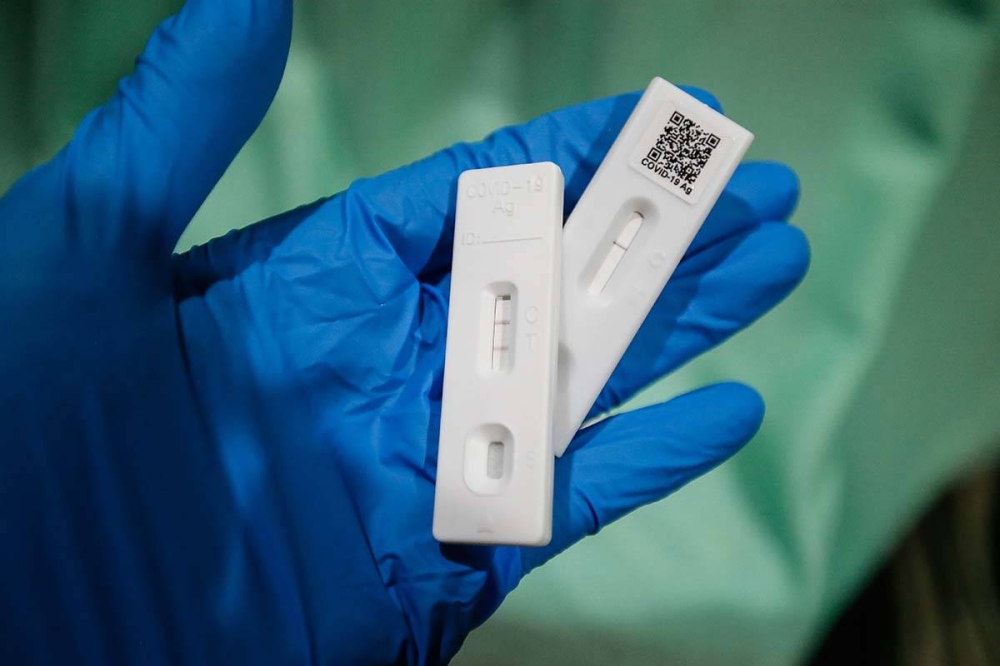 A health worker holds up Covid-19 test strips indicating positive results in Seberang Jaya on April 7, 2022. — Picture by Sayuti Zainudin