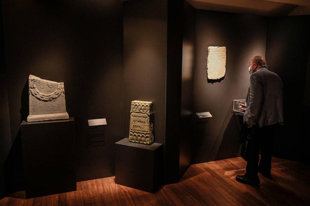 A visitor looks at stelae on display for the exhibition ‘Stone Paths - Stories set in Stone: Jewish Inscriptions in Greece’, at the Jewish Museum of Greece, in Athens May 17, 2022. — AFP pic