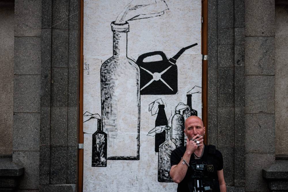Ukrainian street artist Gamlet Zinkivskyi smokes a cigarette while painting on a wooden board on a street in Kharkiv on May 16, 2022, amid the Russian invasion of Ukraine. — AFP pic