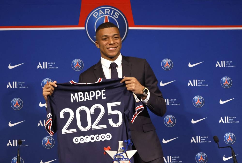 Paris St Germain's Kylian Mbappe poses holding a shirt during a press conference in Paris May 23, 2022. — Reuters pic