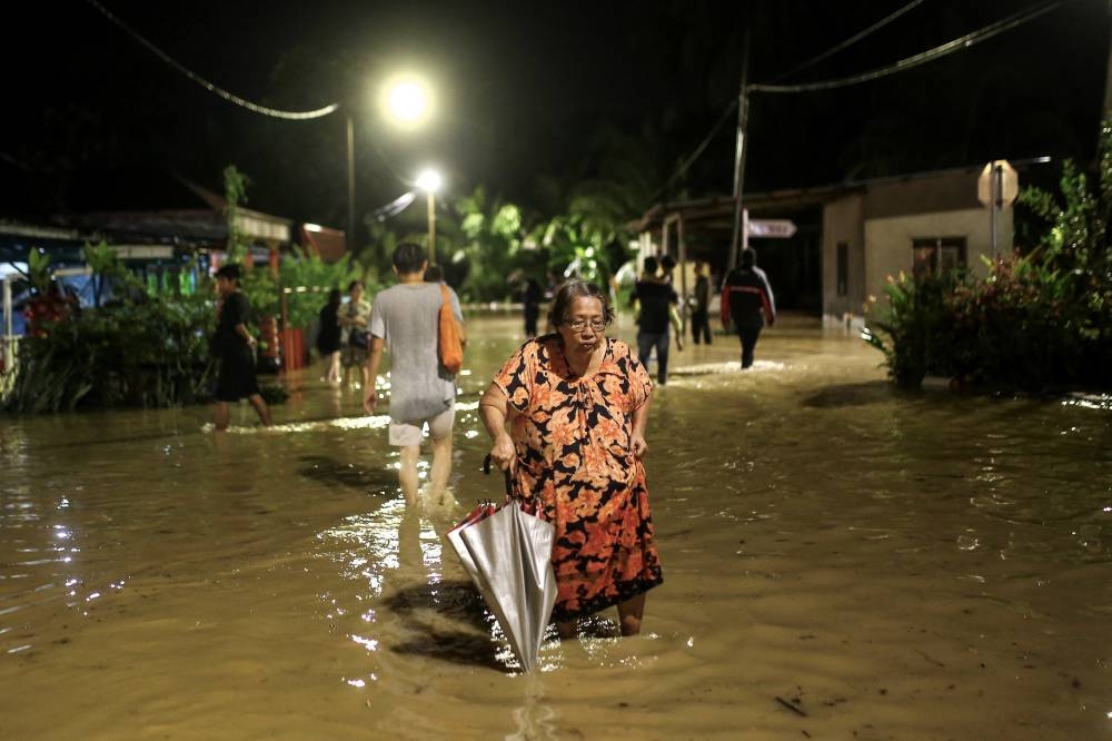 Taman Lee Siew Joo residents wade through floodwaters brought by heavy rain, in Seremban May 24, 2022. — Bernama pic