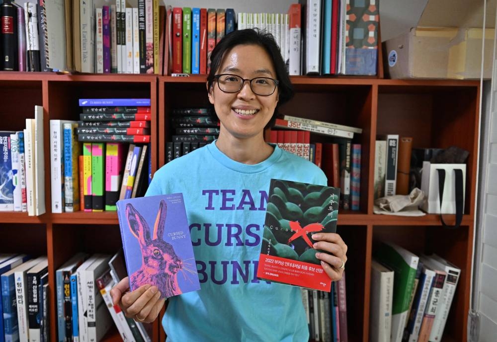 This picture taken on May 17, 2022 shows South Korean horror writer Bora Chung posing with her book ‘Cursed Bunny’ during an interview with AFP at her apartment in the South Korean port city of Pohang. — AFP pic