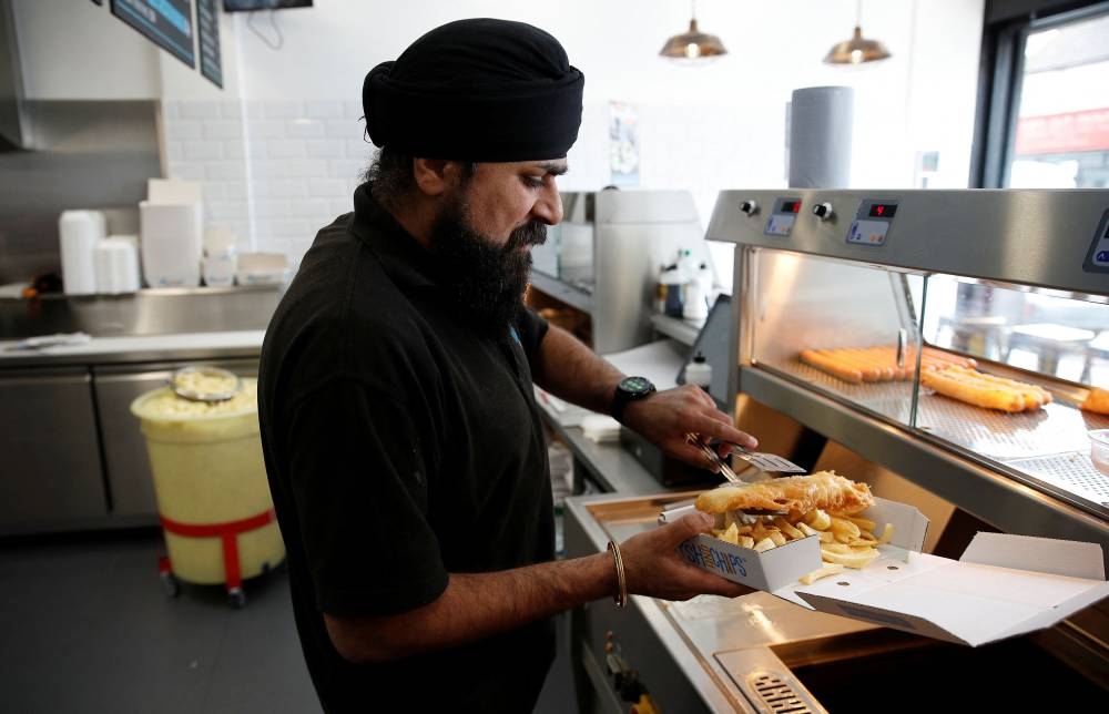 Owner of Hooked Fish and Chips shop, Bally Singh, prepares a portion of fish and chips at his take-away in West Drayton, Britain May 25, 2022. — Reuters pic