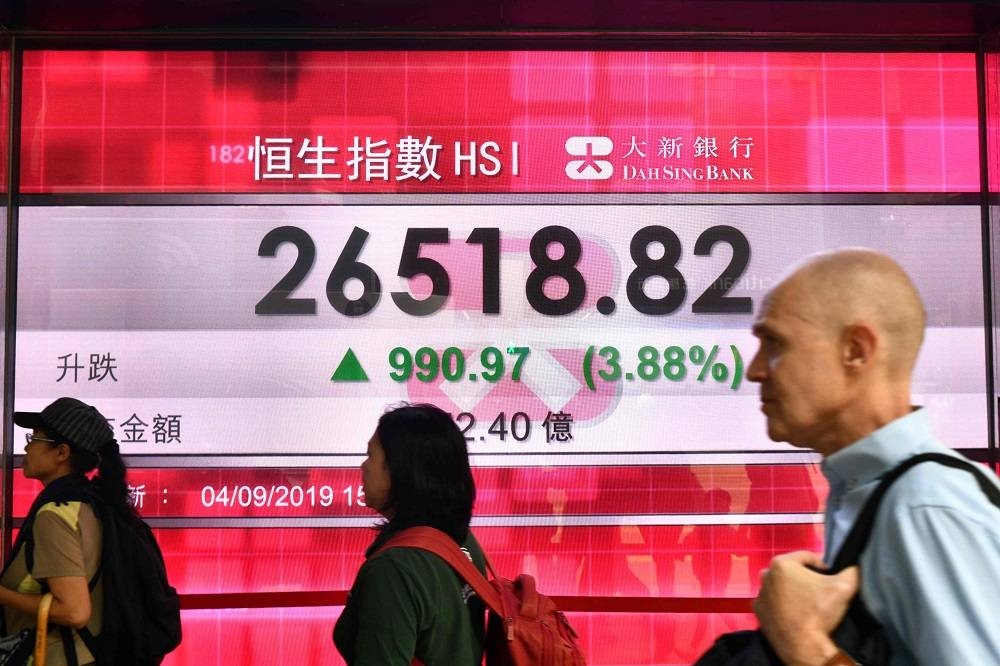 Pedestrians walk past a stocks display panel showing activity of the Hang Seng Index in Hong Kong September 4, 2019. — AFP pic 