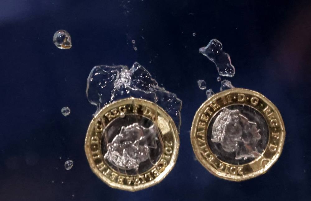 Pound coins plunge into water in this illustration taken, May 23, 2022. — Reuters pic