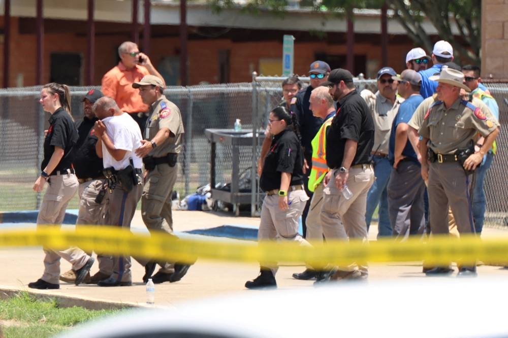 A law enforcement officer is led from the scene while a mass shooting was underway at Robb Elementary School where a gunman killed 19 children and two adults in Uvalde, Texas May 24, 2022. ― Pete Luna/Uvalde Leader-News/Handout via Reuters