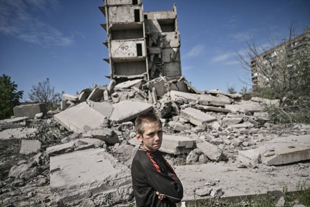 A young boy stands in front of a damaged building after a strike in Kramatorsk in the eastern Ukranian region of Donbas, on May 25, 2022. — AFP pic