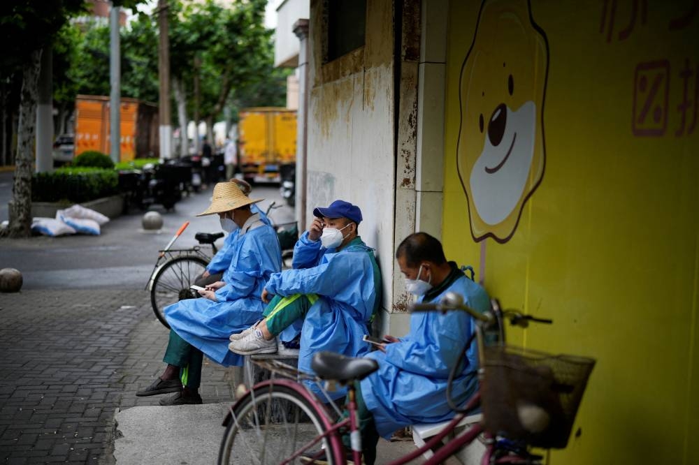 Workers in protective suits rest on a street during lockdown, amid the Covid-19 outbreak, in Shanghai, China, May 28, 2022. — Reuters pic