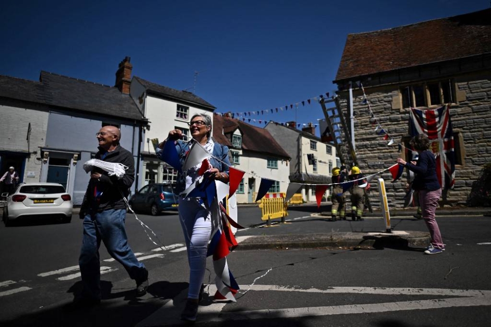 Suze Meredith, Parish chair of Bidford-On-Avon and chair of the Platinum Jubilee committee of the village, helps to install buntings in the streets of Bidford-On-Avon, central England, on May 27, 2022, as preparations get underway for the forthcoming Platinum Jubilee celebrations for Queen Elizabeth II. — AFP pic
