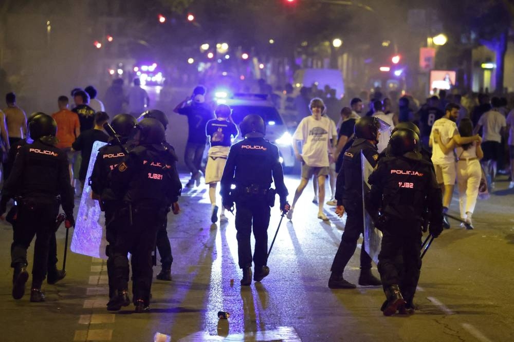 Police officers clash with Real Madrid fans after they won the Champions League Final against Liverpool in Madrid May 29, 2022. — Reuters pic