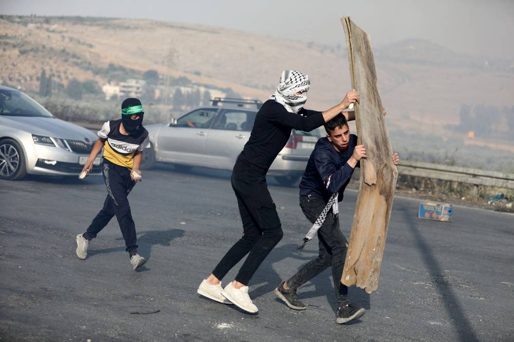 Palestinian men take cover during a protest over tensions in Jerusalem's Al-Aqsa Mosque, at Huwara checkpoint, near Nablus in the Israeli-occupied West Bank May 29, 2022. ― Reuters pic