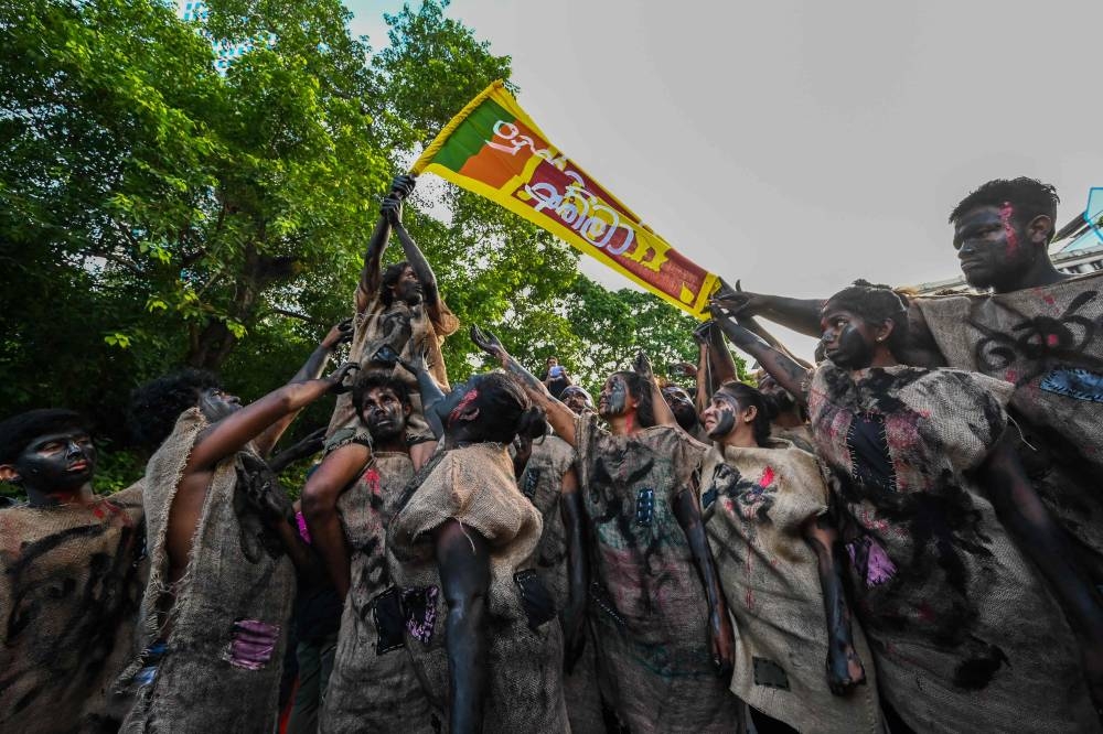 Demonstrators with their faces painted hold a Sri Lankan flag during the 50th day of anti-government protests demanding the resignation of Sri Lanka's President Gotabaya Rajapaksa over the country's crippling economic crisis, in Colombo on May 28, 2022. — AFP pic
