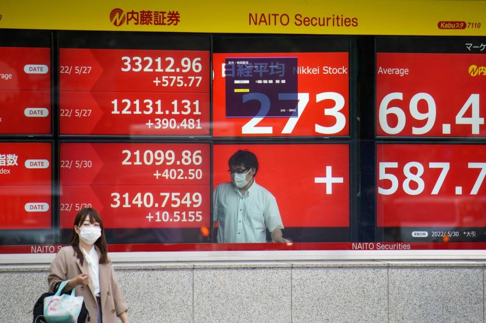A woman walks past an electronic share price board showing the closing numbers on the Tokyo Stock Exchange in Tokyo on May 30, 2022. — AFP pic