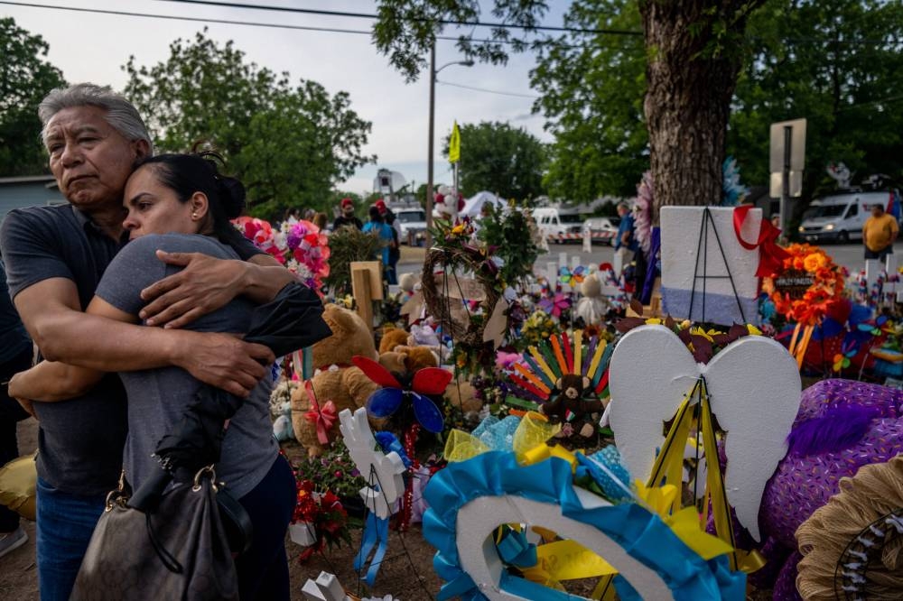 A couple stands together as they pay their respects at a memorial dedicated to the 19 children and two adults killed on May 24th during the mass shooting at Robb Elementary School in Uvalde, Texas May 31, 2022.  — AFP pic