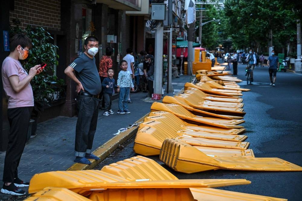 People stand next to barriers, erected on March 19 according to local residents as part of pandemic lockdowns in the area and taken down in the Jing' an district of Shanghai on May 31, 2022, as the city prepares to lift more curbs after two months of heavy-handed restrictions. — AFP pic