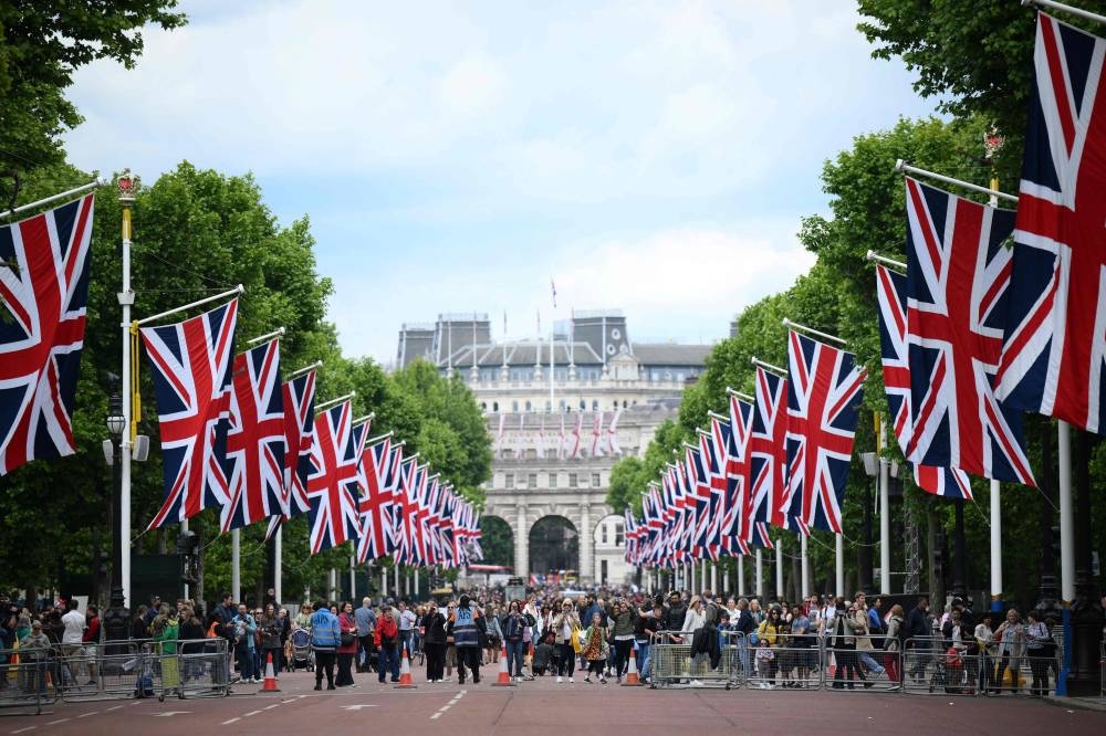 People gather of The Mall, in London, on June 1, 2022 as the Union flags flutter in the wind ahead of the Platinum Jubilee's celebrations for Britain's Queen. — AFP pic