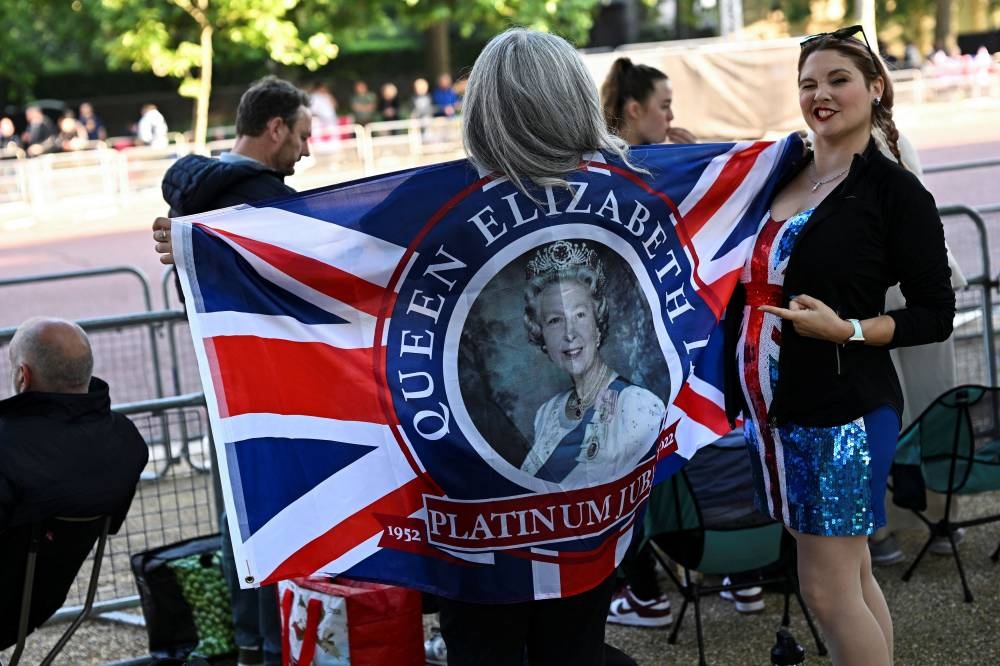 Women hold a flag with Britain's Queen Elizabeth's picture on it during the Queen's Platinum Jubilee celebrations in London, Britain June 2, 2022. — Reuters pic