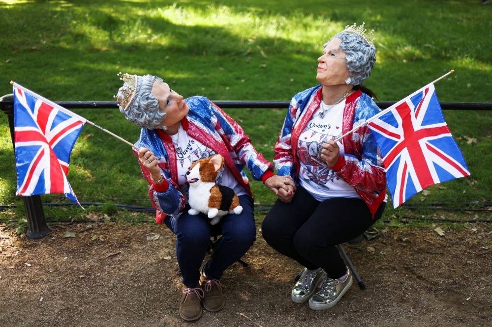 Carol Bysshe from Cape Town and her sister Jenny Parris from London wear masks of Britain's Queen Elizabeth as royal enthusiasts gather along The Mall for the Queen's Platinum Jubilee celebrations in London June 2, 2022. — Reuters pic
