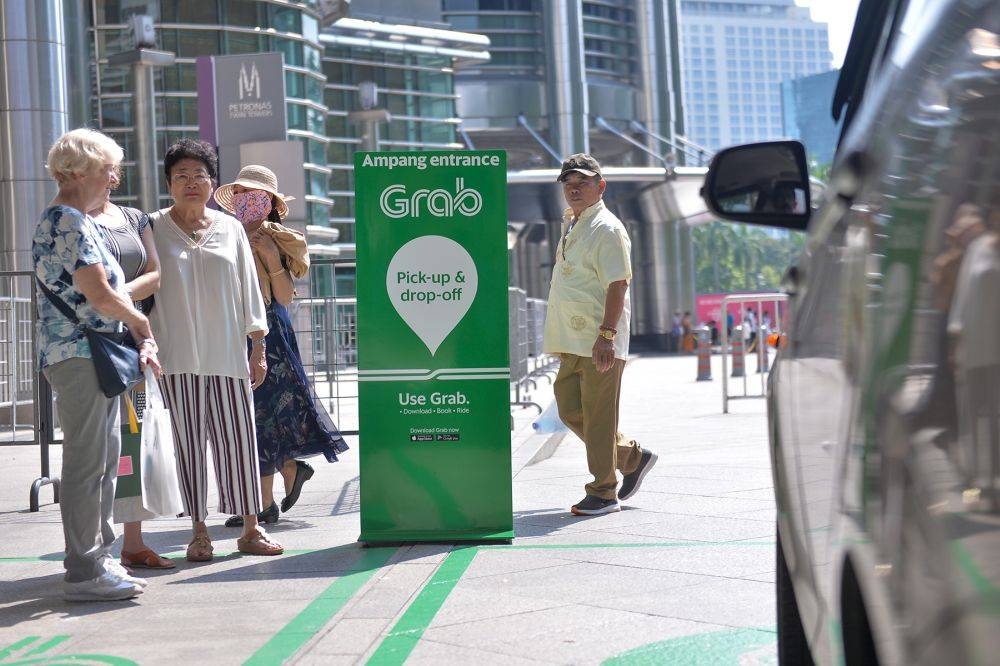 Passengers wait for their Grab rides at Suria KLCC, Kuala Lumpur July 12, 2019. — Picture by Mukhriz Hazim