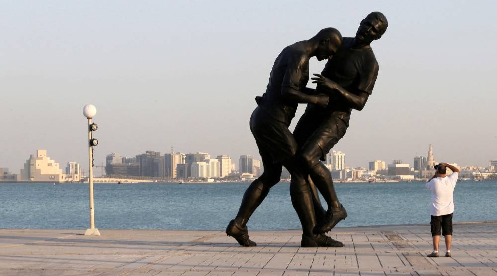 A man takes pictures of a bronze sculpture titled ‘Coup de Tete’ by Algerian-born French artist Adel Abdessemed during its installation on the Corniche in Doha October 7, 2013. — Reuters pic 