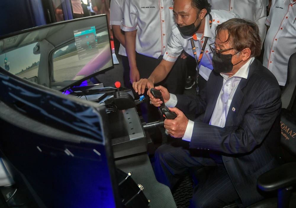 Sarawak Premier Tan Sri Abang Johari Openg tries using a flight stimulator machine at the International Symposium on Digital Industry Transformation 2022 in Kuching June 7, 2022. — Bernama pic