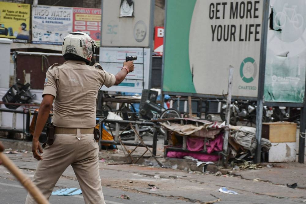 A policeman aims a handgun at demonstrators during a protest against former India’s Bharatiya Janata Party spokeswoman Nupur Sharma and her remarks about Prophet Mohammed, in Ranchi on June 10, 2022. — AFP pic