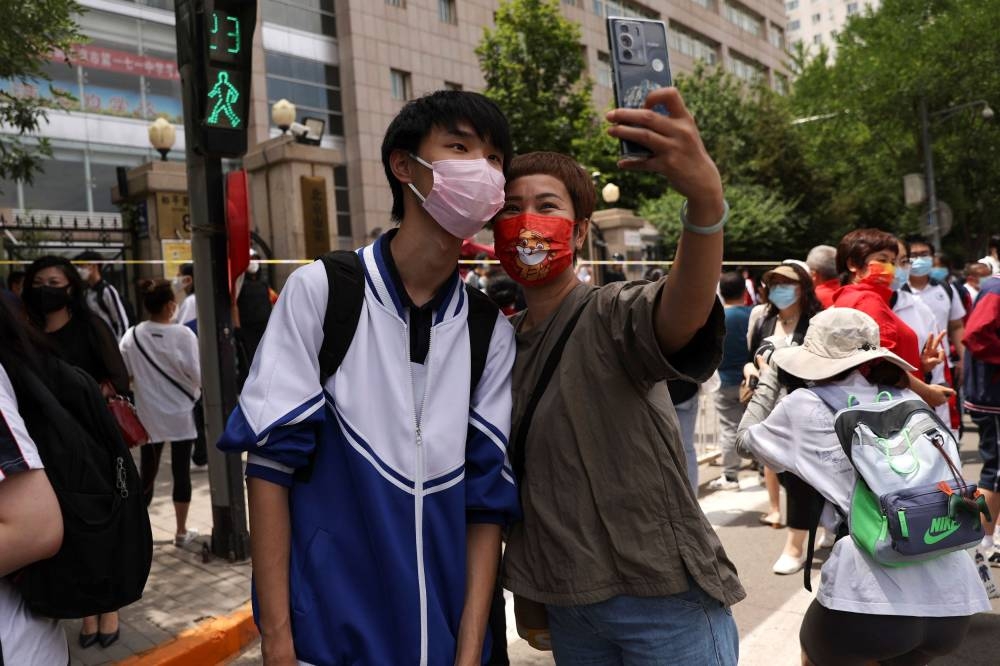 A student poses with his parent after finishing an exam, during the annual national college entrance exam, or ‘gaokao’, amid the Covid-19 outbreak, at a high school in Beijing, China June 7, 2022. — Reuters pic