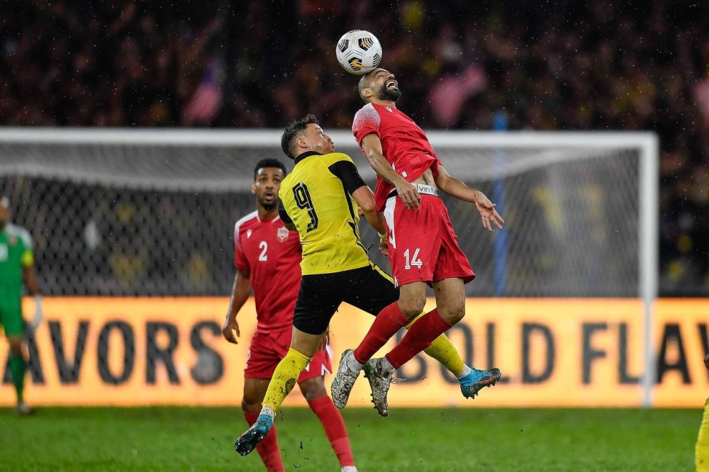 Harimau Malaya player Darren Lok competes in an airball with Bahrain player Ali Abdula Haram (right) in the Group E match of the 2023 Asian Cup Qualifier Final at the Bukit Jalil National Stadium, Kuala Lumpur, June 11, 2022. — Bernama pic