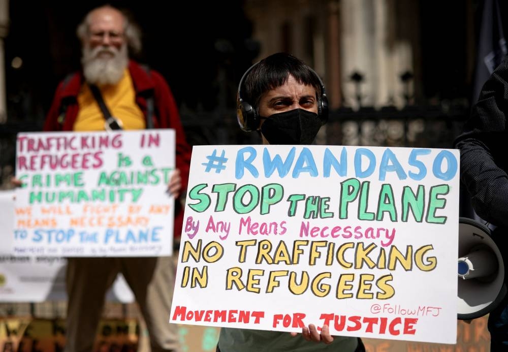 Demonstrators display placards during a protest outside the Royal Courts of Justice whilst a legal case is heard over halting a planned deportation of asylum seekers from Britain to Rwanda, in London June 13, 2022. — Reuters pic