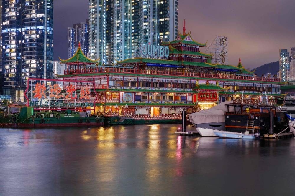 This long-exposure photo taken on June 12, 2022 shows the Jumbo Floating Restaurant located in the typhoon shelter near Aberdeen on the south side of Hong Kong island, partially boarded up in preparation for a reported voyage out of the city. — AFP pic