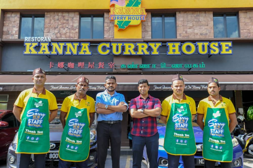 Kanna Curry House general manager (in blue) Siva and and manager, Yoga Kannan (red) together with staff. during at the Puchong outlet. — Picture by Shafwan Zaidon