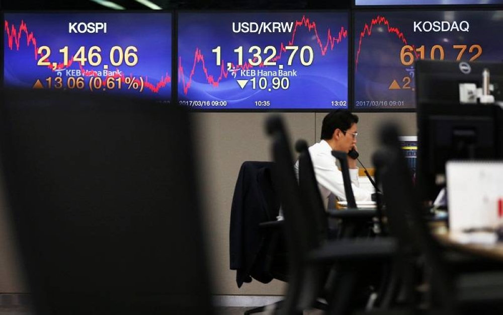 A currency dealer works in front of electronic boards showing the Korea Composite Stock Price Index (Kospi). ― Reuters pic