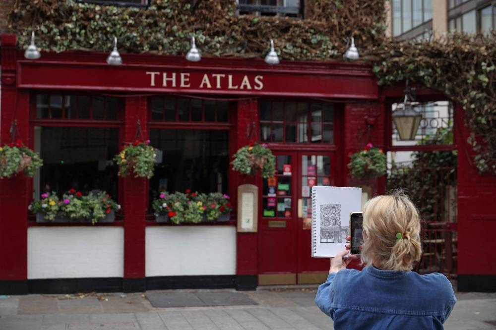 Artist Lydia Wood holds up her finished drawing of The Atlas pub in west London on May 26, 2022. — AFP pic