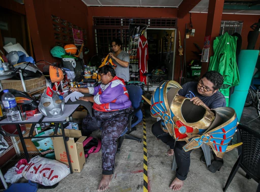 Asyraf (left) with friends Syed Hamizan Syad Sharuddin and Syed Zulhimi Syad Sharuddin preparing their costumes for a cosplay competition in Kuala Lumpur next month. — Picture by Farhan Najib 