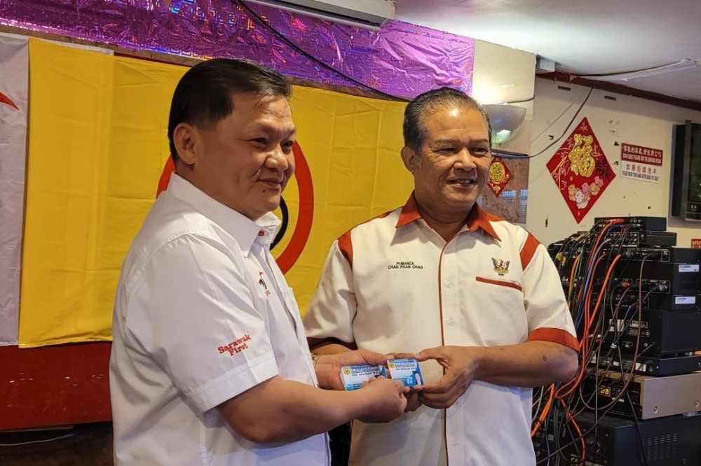 Huang (left) presents SUPP membership card to Chan. ― Borneo Post pic