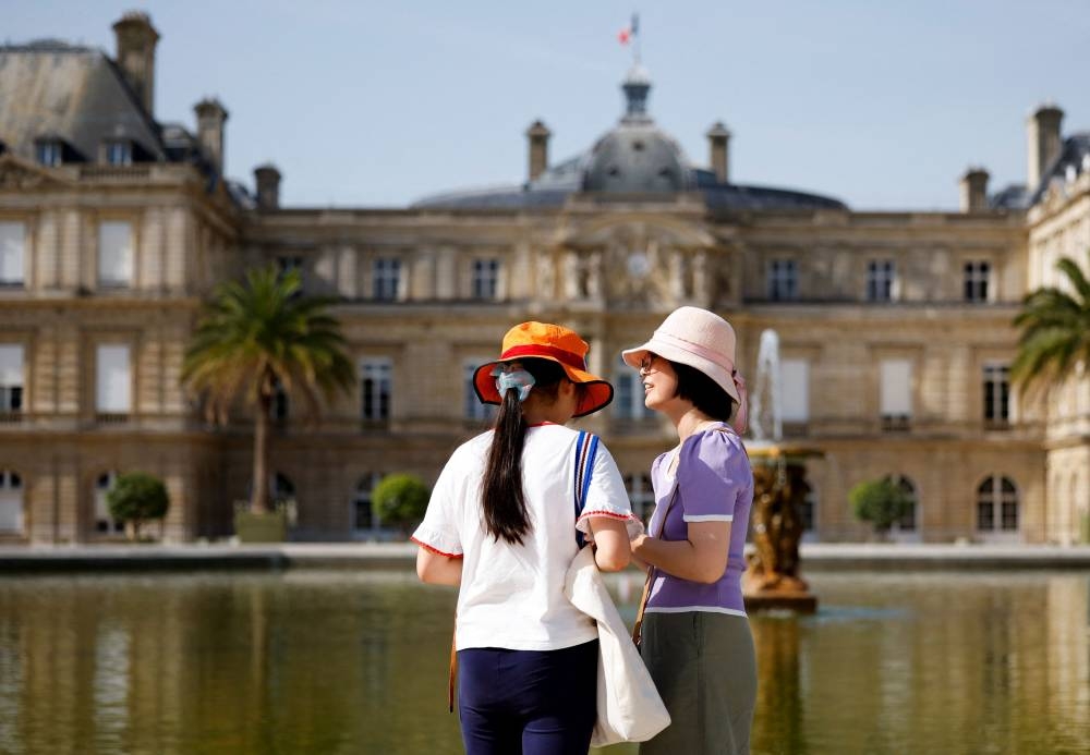 Women wearing hats to protect themselves from the sun talk near a public fountain at the Luxembourg Gardens as an early heatwave hits the country, in Paris, France, June 17, 2022. ― Reuters pic