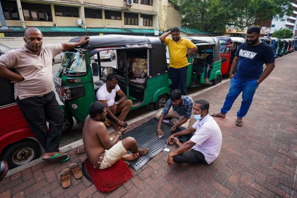 Autorickshaw drivers play a cards game while queueing to buy petrol from a Ceylon petroleum corporation fuel station in Colombo on June 18, 2022. — AFP pic