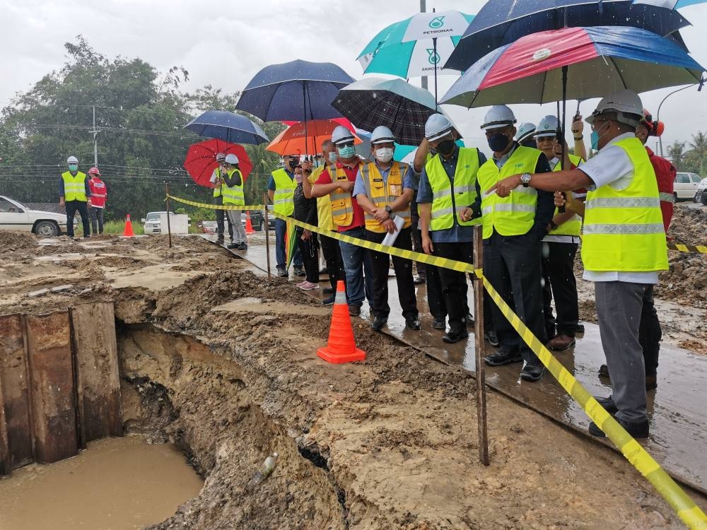 Julaihi (front, second right) being briefed by Daniel (front, right) during the inspection on the burst-pipe site. Seen on the minister’s right is Dr Abdul Rahman. — Borneo Post Online pic