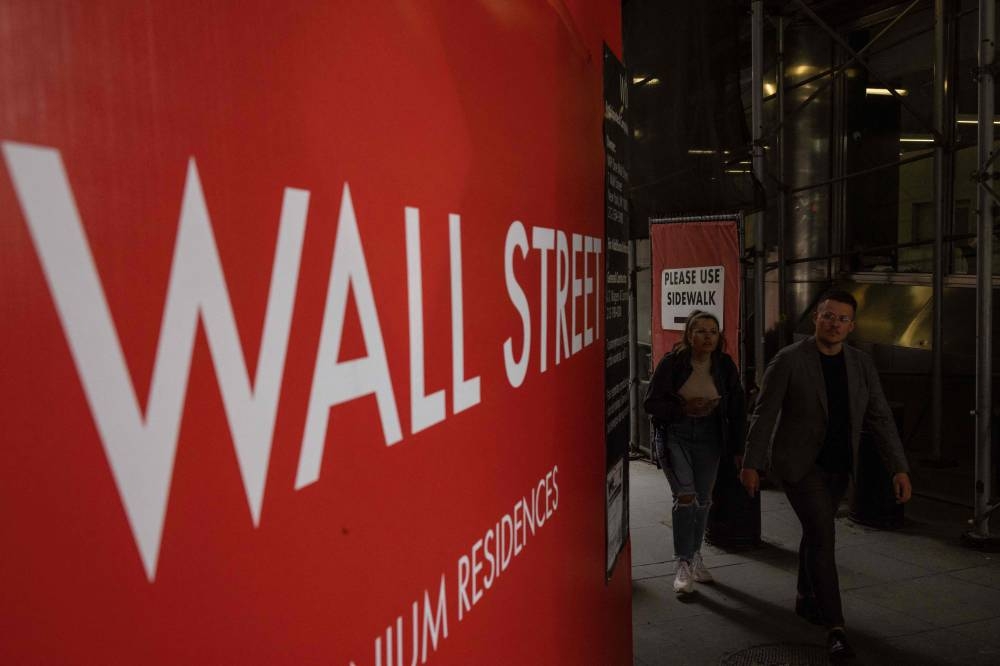 People walk along a Wall Street sign in New York on June 16, 2022. — AFP pic