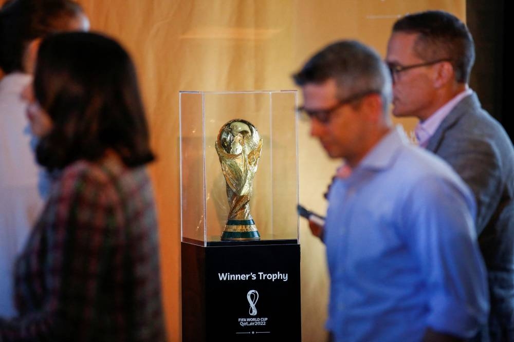 People walk next to the official Fifa World Cup Trophy as it is displayed during a news conference in New York City June 17, 2022. — Reuters pic