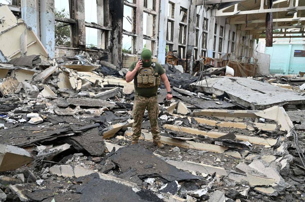 A Ukrainian serviceman talks by phone as he walks through the rubbles of a  building of the Polytechnic Sports Complex of the Kharkiv National Technical University after it was hit by Russian missile in Kharkiv on June 24, 2022, amid Russian invasion of Ukraine. — 