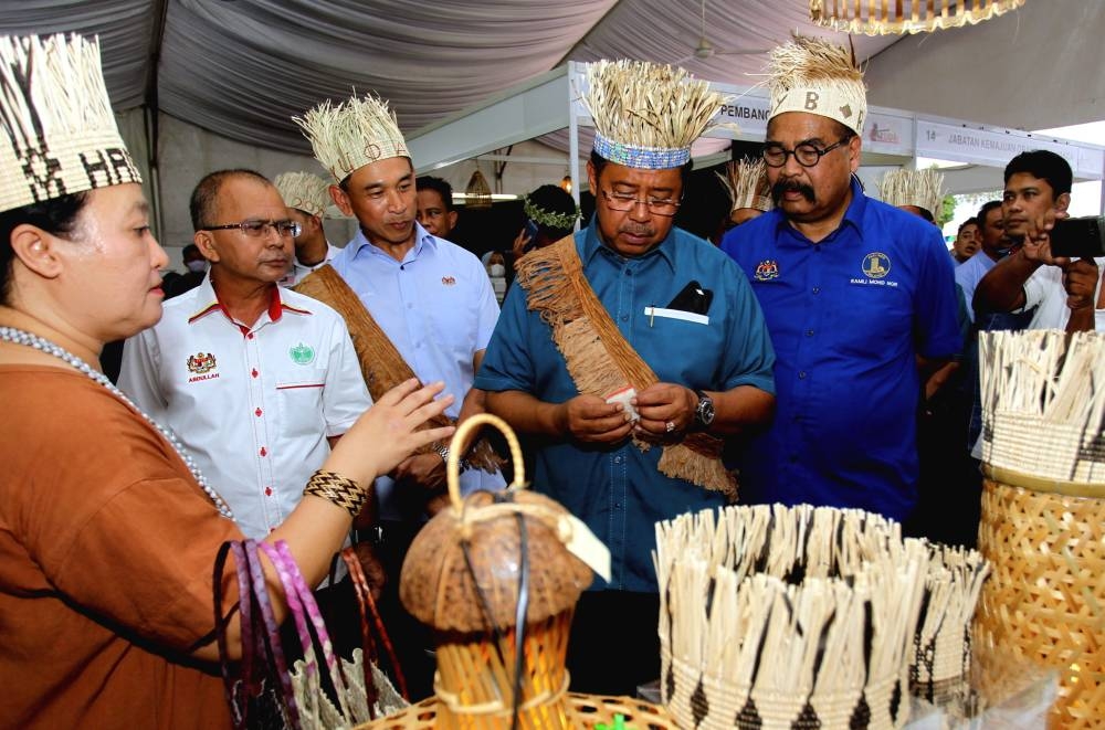 Datuk Seri Abdul Rahman Mohamad (second right) looks on at an Orang Asli craft at the Orang Asli Entrepreneurship Carnival in Meru, June 25, 2022. — Bernama pic