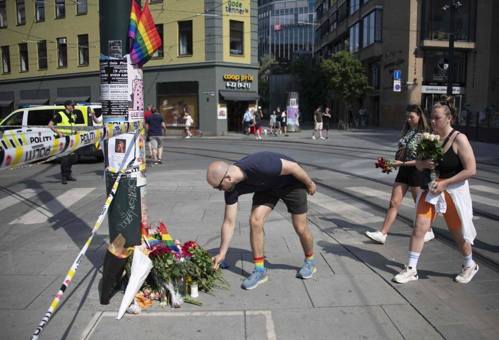 People lay down flowers at a crime scene on June 25, 2022, in the aftermath of a shooting outside pubs and nightclubs in central Oslo killing two people, injuring 21. — AFP pic 