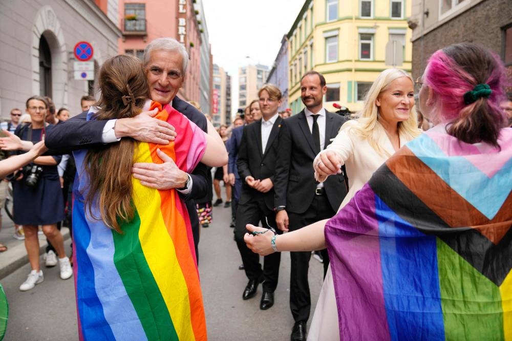 Norwegian Prime Minister Jonas Gahr Store and Crown Princess Mette-Marit of Norway hug people with a rainbow and progress flag as they visit a crime scene on June 25, 2022, in the aftermath of a shooting outside pubs and nightclubs in central Oslo killing two people injuring 21. — Norway OUT pic via AFP