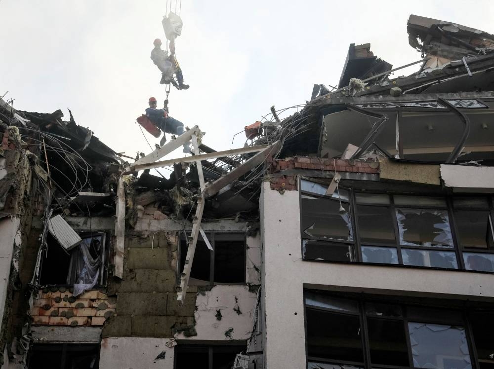 Rescue workers are elevated by a crane, at an apartment building destroyed in a missile strike, amid Russia's invasion of Ukraine, in Kyiv, Ukraine June 26, 2022. — Reuters pic