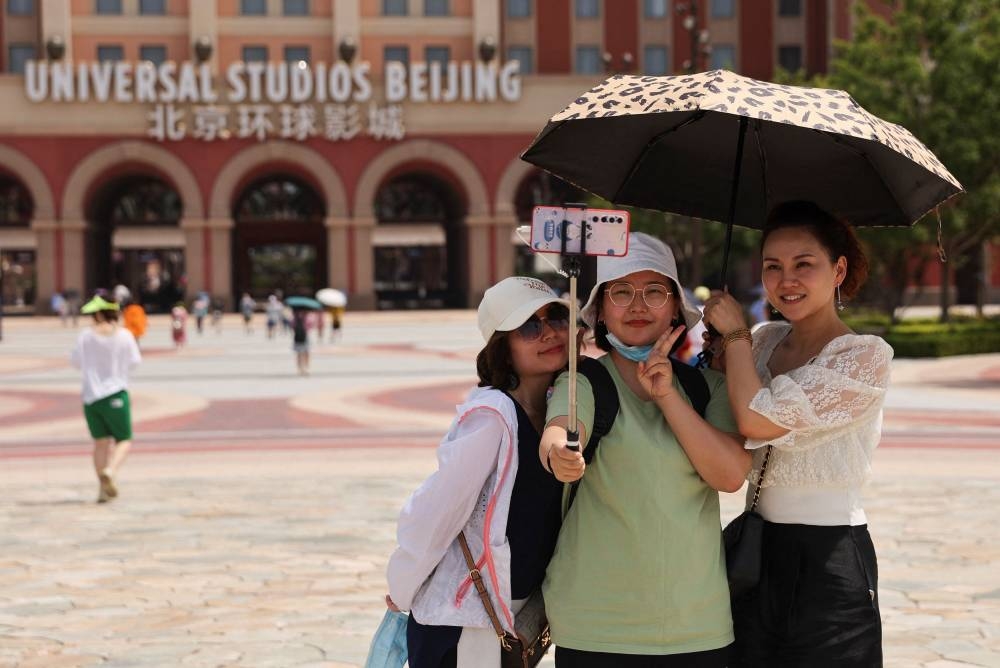 Tourists take selfies in front of the Universal Studios theme park as it reopens to the general public following the coronavirus disease (Covid-19) outbreak in Beijing, China June 25, 2022. — Reuters pic